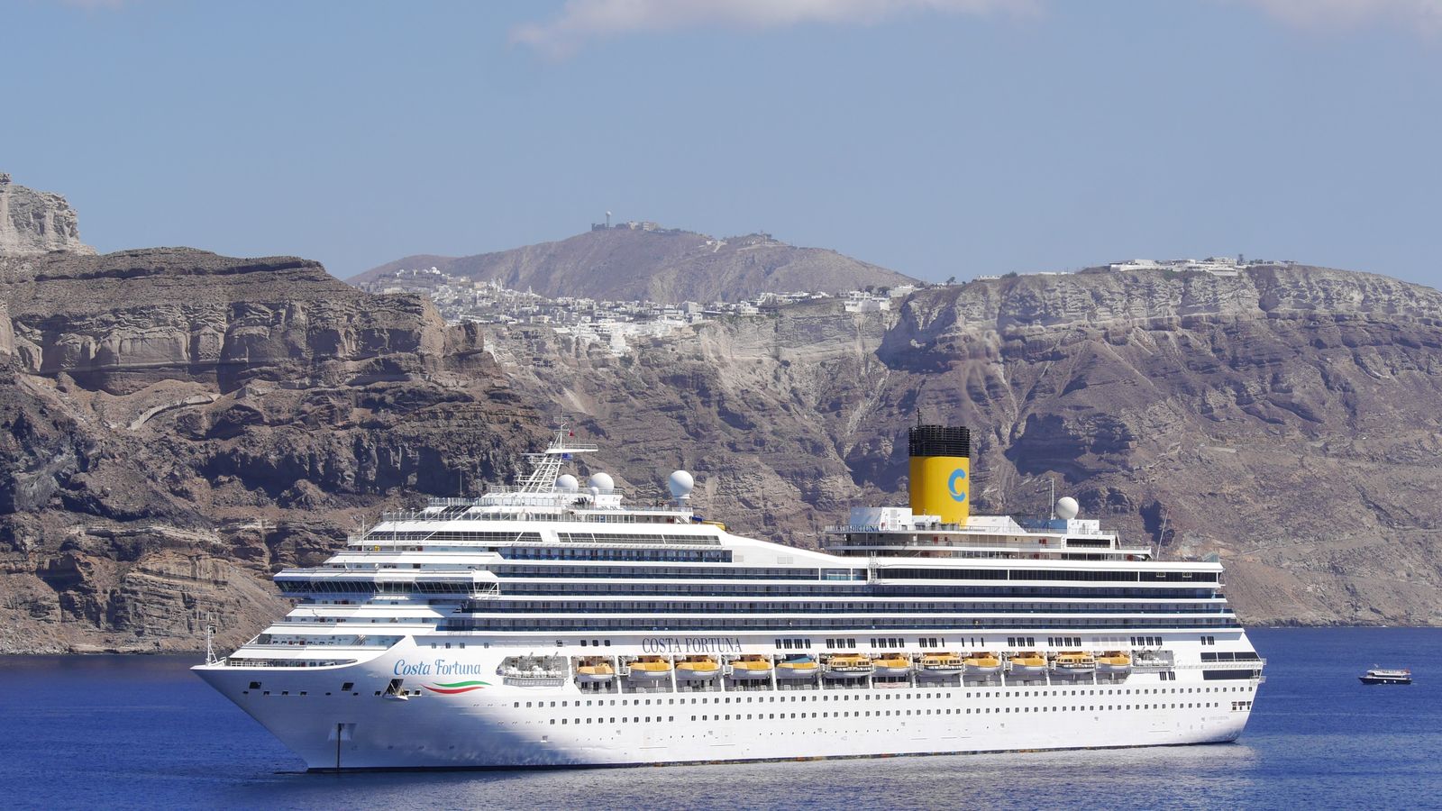 Luxury Mediterranean cruise ship near Santorini cliffs in Greece